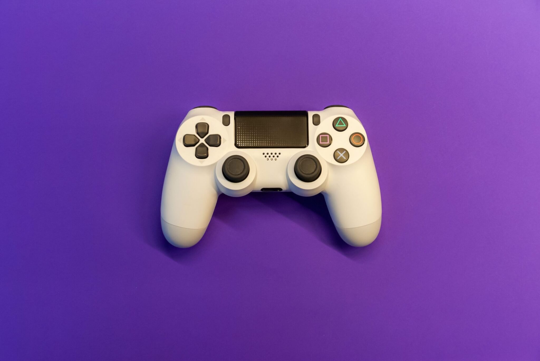 White PlayStation 4 Controller on Purple Backdrop
